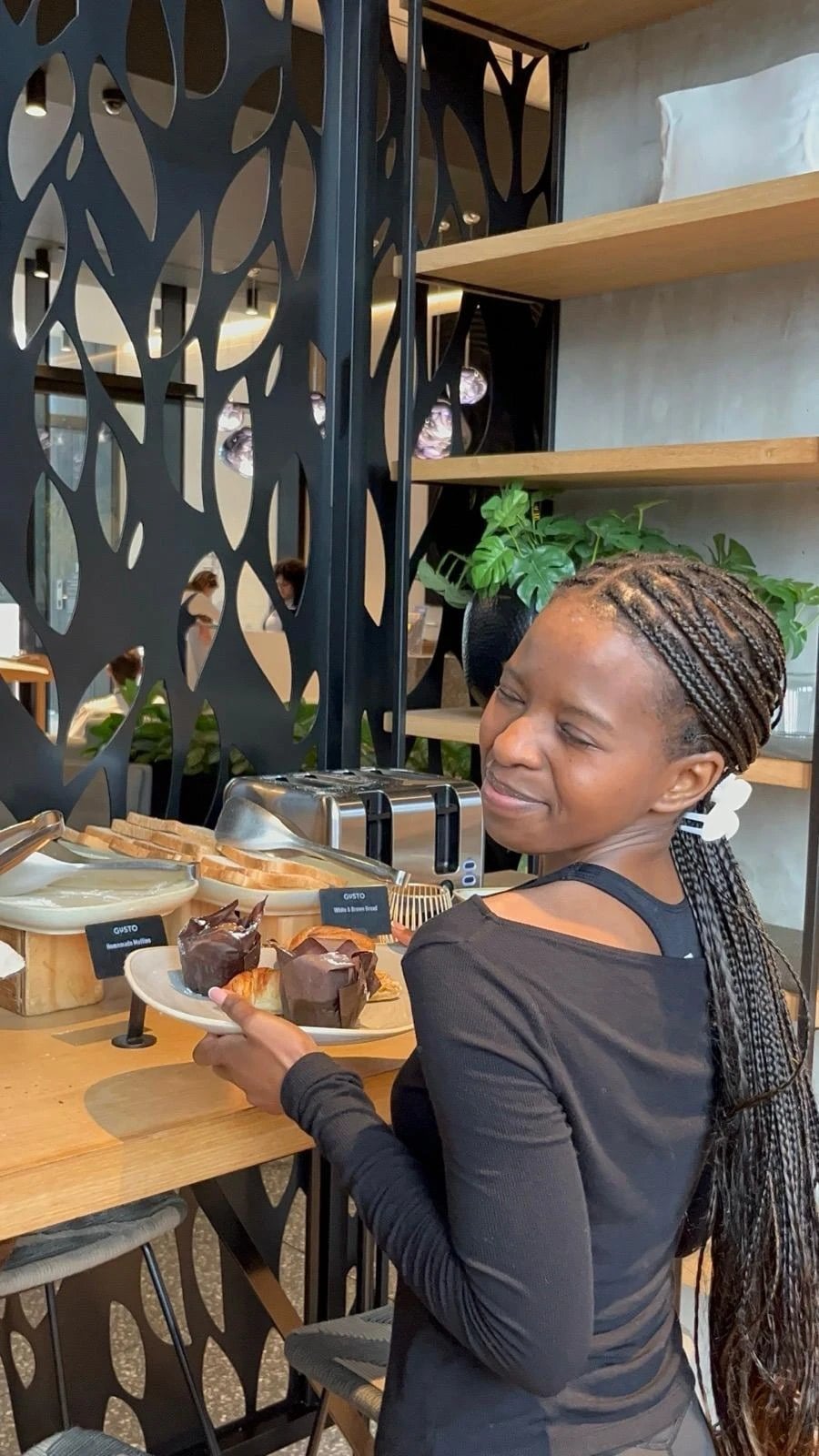 A woman smiling over a plate of muffins and pastries