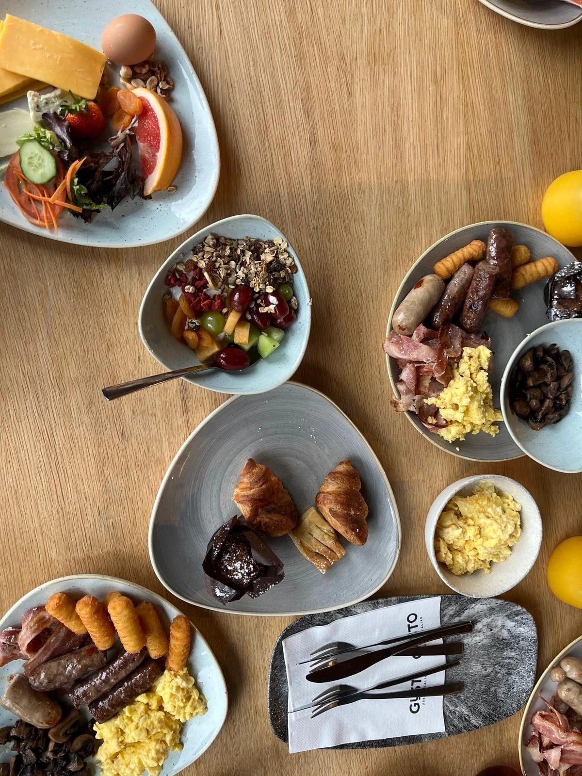 Plates of brunch from above: pastries, fruit, eggs and more