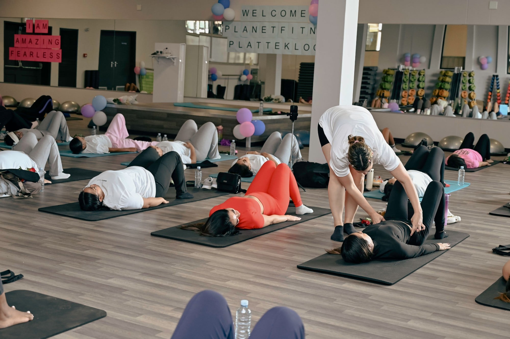 A coach guiding a woman through a glute bridge